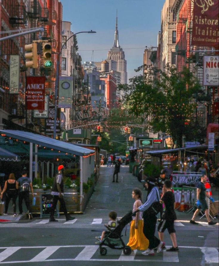 people are crossing the street at an intersection in new york city, with tall buildings behind them