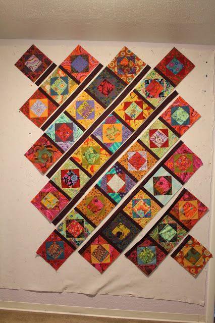 a wall hanging made up of many different colored pieces of fabric and paper on the wall