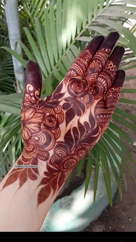 a hand with henna on it and palm trees in the backgroung