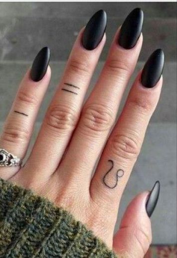 someone with black nail polish and tattoos on their fingers is showing off her ring finger tattoo