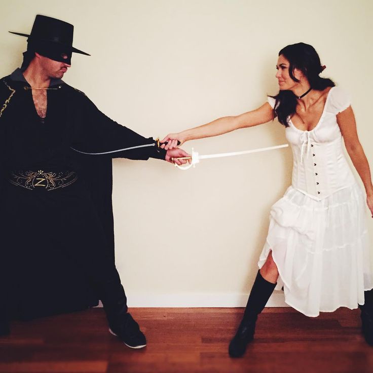 a man and woman dressed up in costume holding hands with each other while standing against a wall