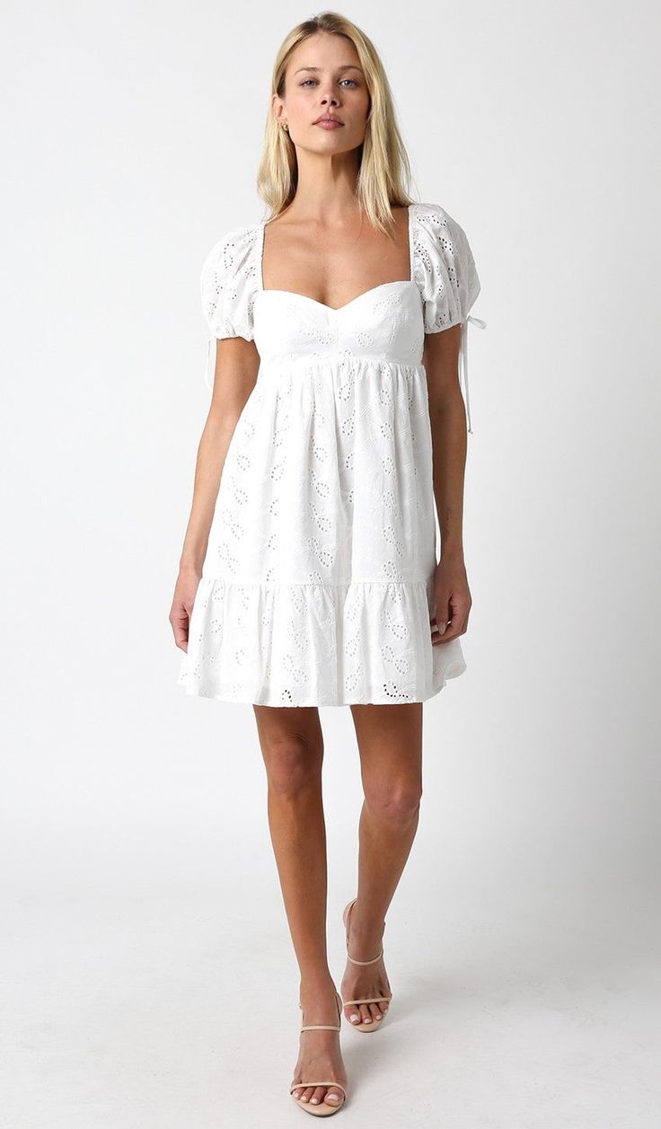 Introducing the Jessie White Eyelet Babydoll Mini Dress - the perfect piece to throw on for a fun and effortless brunch with friends. With its eye-catching eyelet design, you'll turn heads while comfortably enjoying your day. Brunch just got a whole lot more fashionable (and easy)! This flirty mini dress features a sweetheart neckline, empire bodice, and puffy short sleeves with playful ties and elasticized cuffs. Made from white eyelet lace, it's perfect for a fun summer look! The babydoll silh Cute Cotton Mini Dress For Brunch, Eyelet Short Sleeve Dresses For Brunch, Short Sleeve Eyelet Dress For Brunch, Baby Doll Dress White, Cute Spring Lace Mini Dress, Cute Lace Mini Dress For Spring, Cotton Eyelet Mini Dress For Summer, Casual Eyelet Dress For Brunch, Broderie Anglaise Mini Dress With Short Sleeves For Brunch