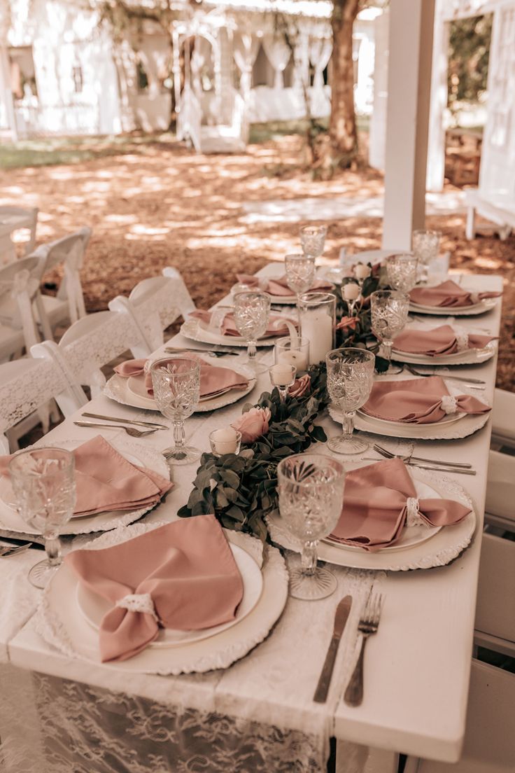 the table is set with pink napkins and place settings