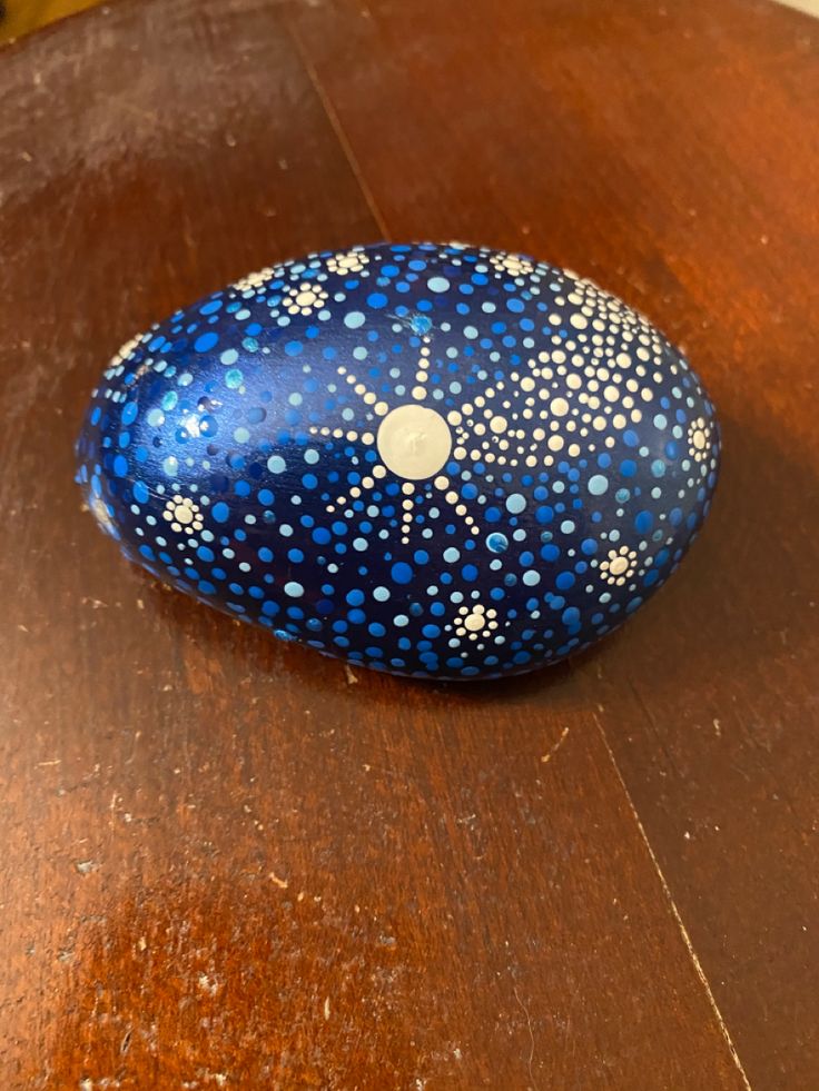 a blue painted rock sitting on top of a wooden table next to a cell phone