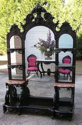 an ornate mirror with pink chairs in front of it