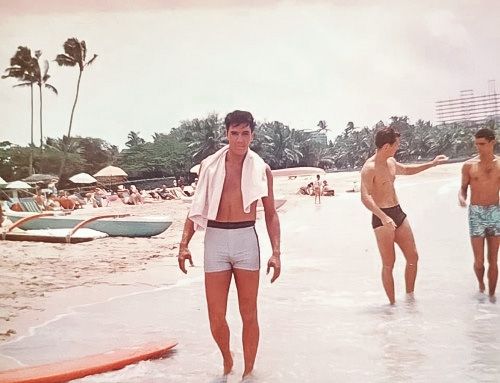 two men in swim trunks are walking into the water