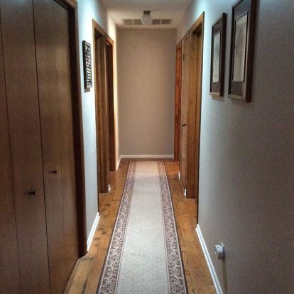 an empty hallway leading to another room with pictures on the wall and carpeted floor