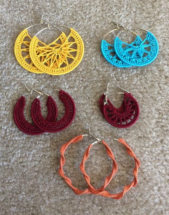 four pairs of crocheted hoop earrings laying on top of a carpeted floor