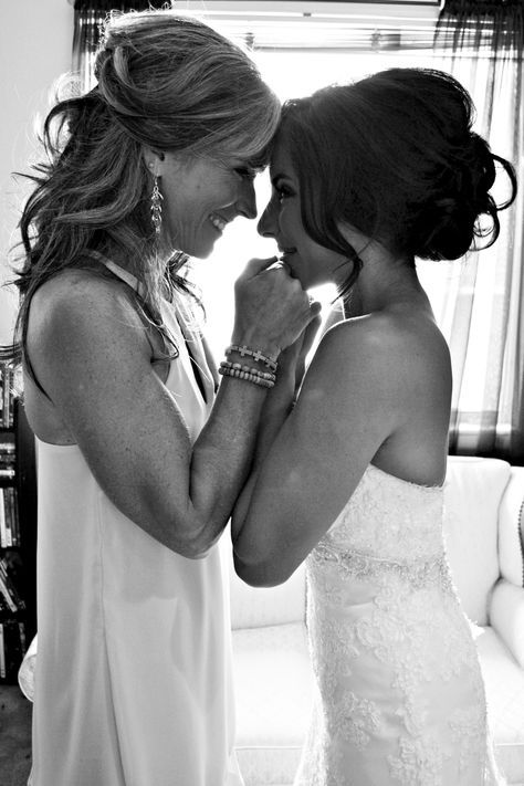 two women standing next to each other in front of a window and one is touching her face