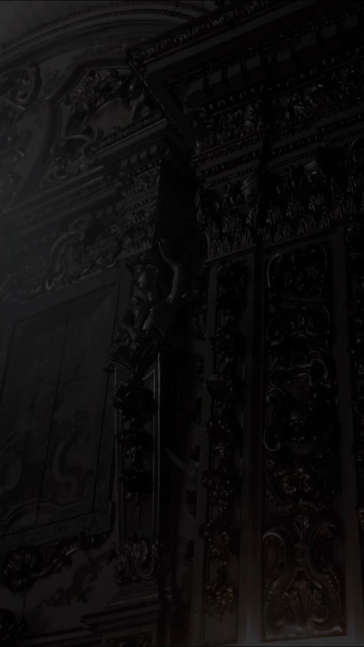 a man in a suit and tie standing next to a wall with ornate carvings on it