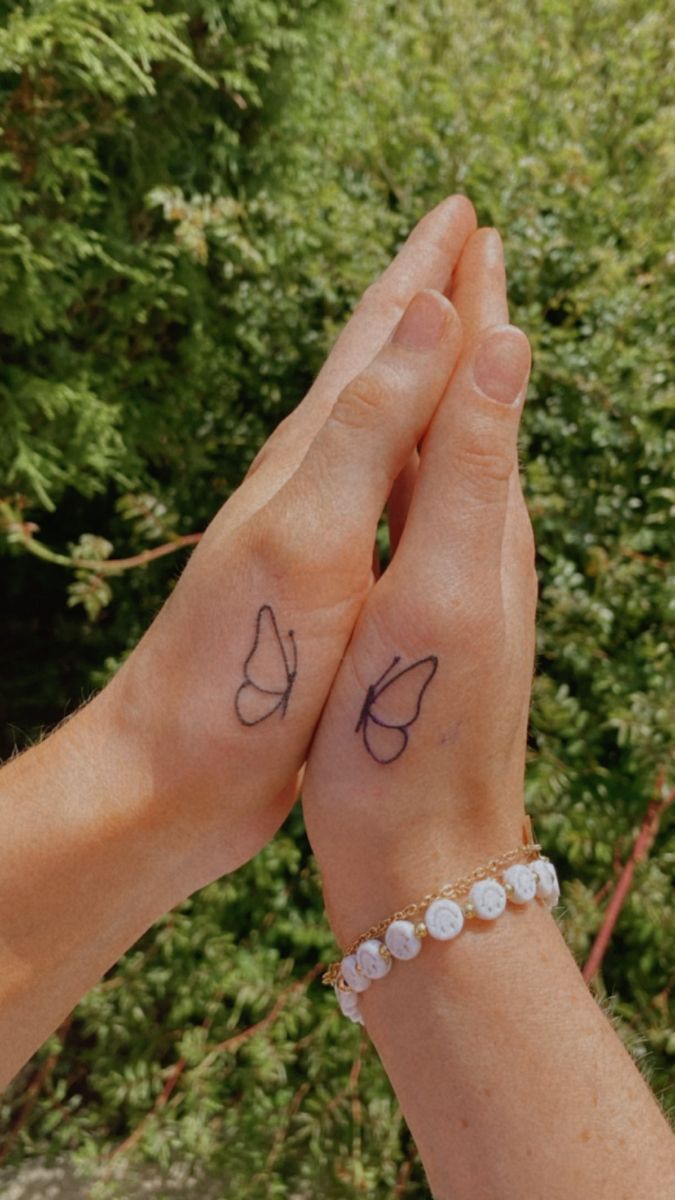 two people holding hands with small tattoos on them