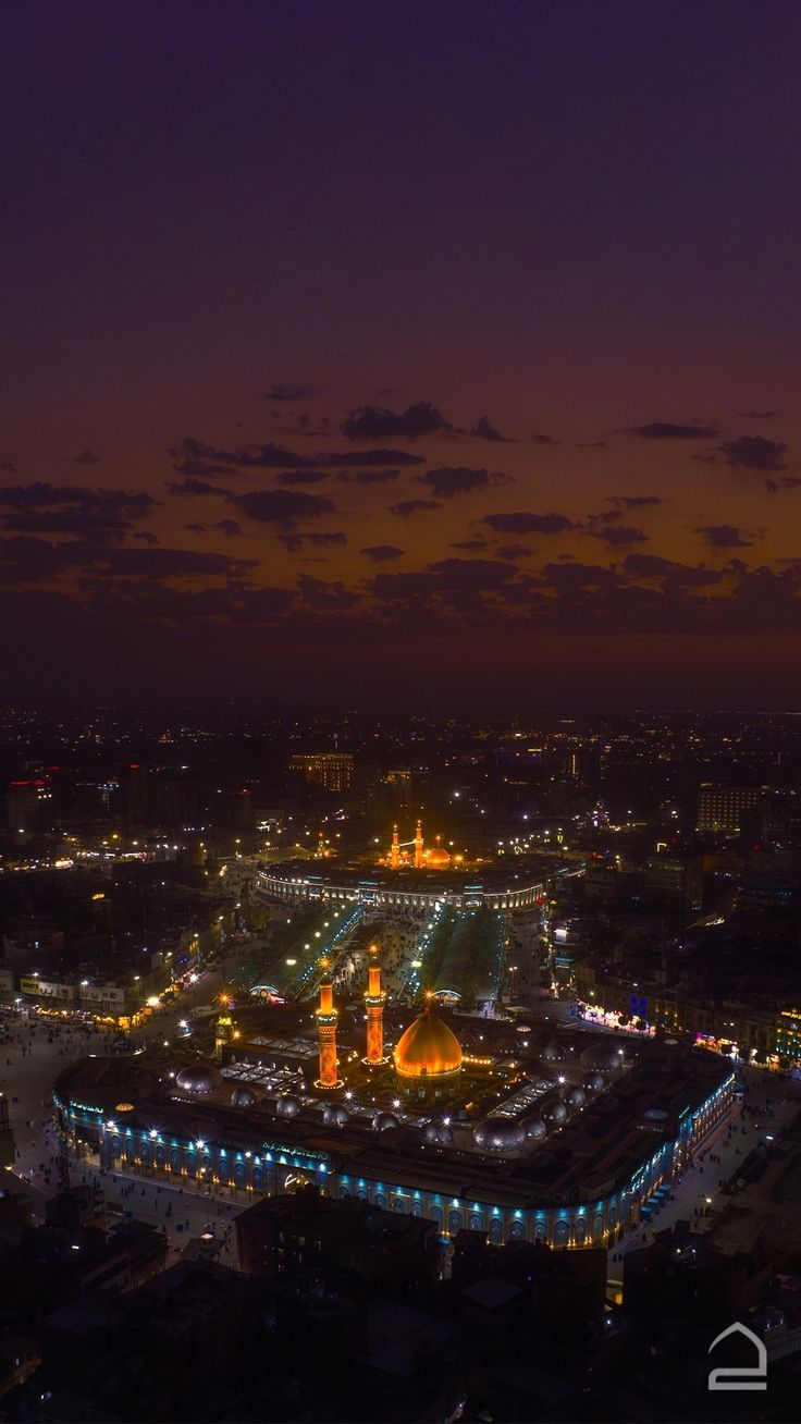 an aerial view of a city at night with the lights on and buildings lit up