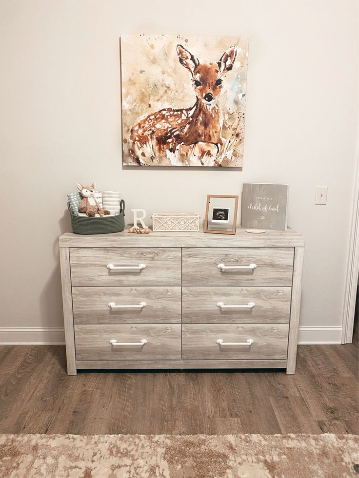 a dresser with a painting on the wall above it