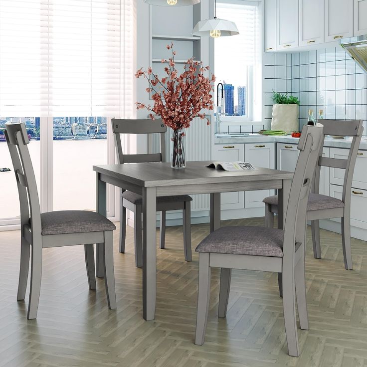 a dining room table with chairs and a vase filled with flowers on top of it