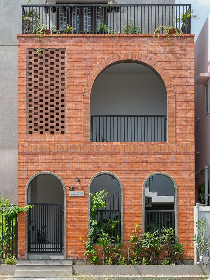 an orange brick building with two balconies on the second floor