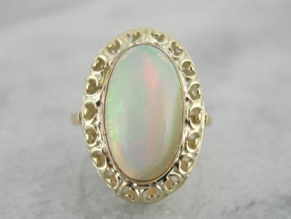 The frame work of this ring is a combination of yellow and green gold, a lovely Art Nouveau look! The open work allows plenty of light in to the center of the stone, allowing the bright orange and green to really shine through. The simple bezel around the stone protects it from wear, and still allows the opal to glow! Metal: 14K Yellow and Green Gold Stone: Ethiopian Opal weighing 5.95 ct Accents: none Time Period: Vintage Ring with New Stone Size of Ring: 7 Marks: 14K Green Goldstone, Frame Work, Colored Stone Rings, Orange And Green, Gold Stone, Filigree Ring, Yellow And Green, Art Deco Jewelry, Vintage Ring