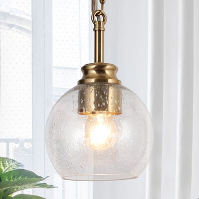 a glass globe light hanging from a ceiling fixture in a room with white curtains and potted plants