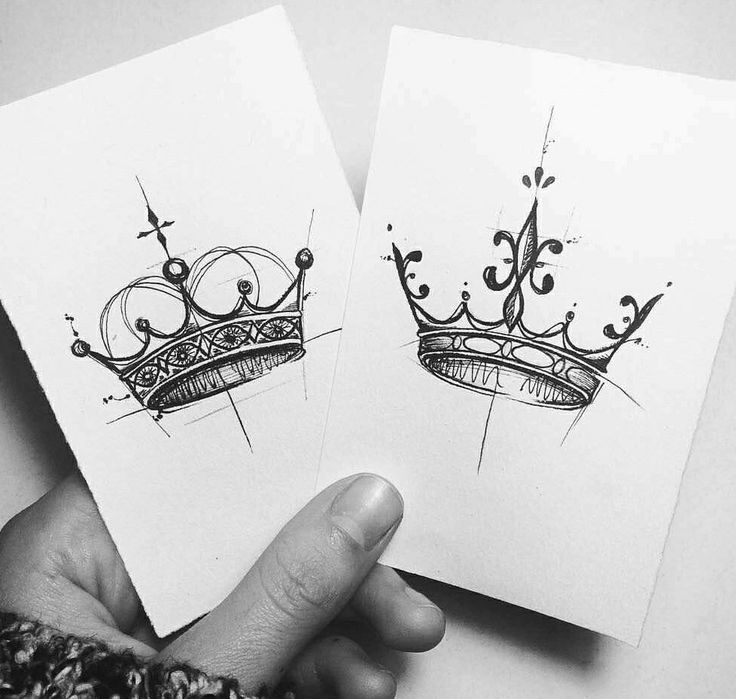 two cards with crowns drawn on them are held in the palm of someone's hand