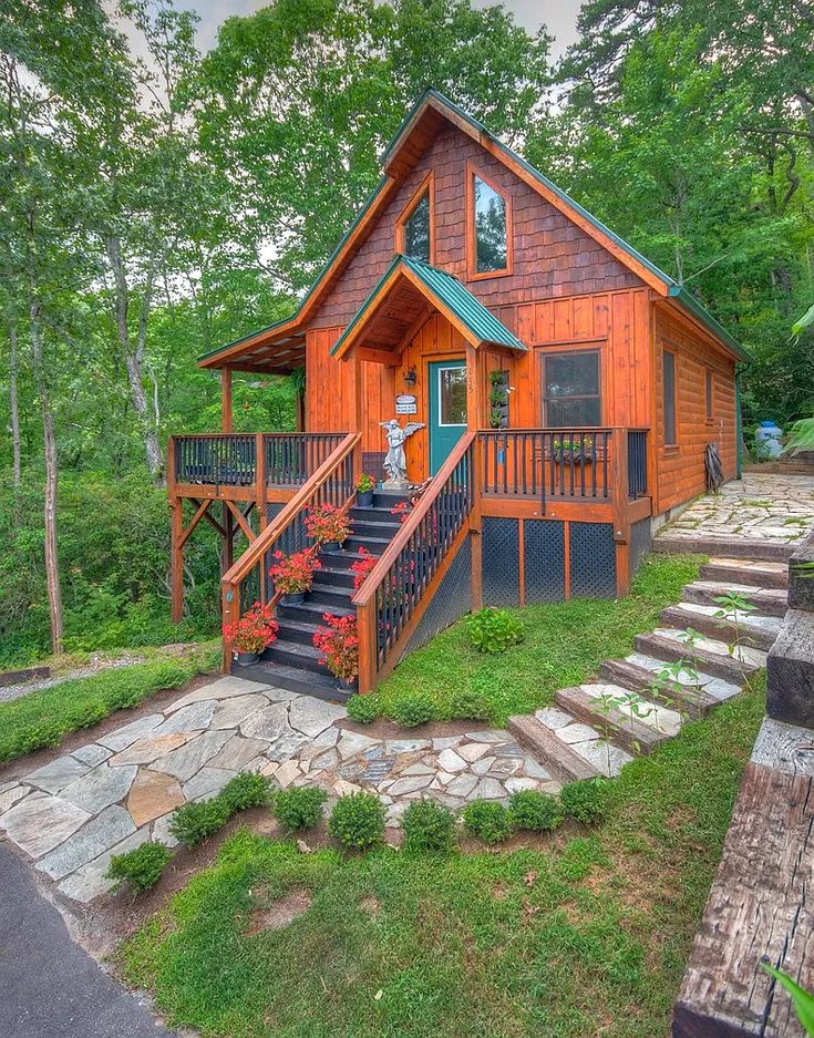 a small cabin in the woods with stairs leading up to it's second floor