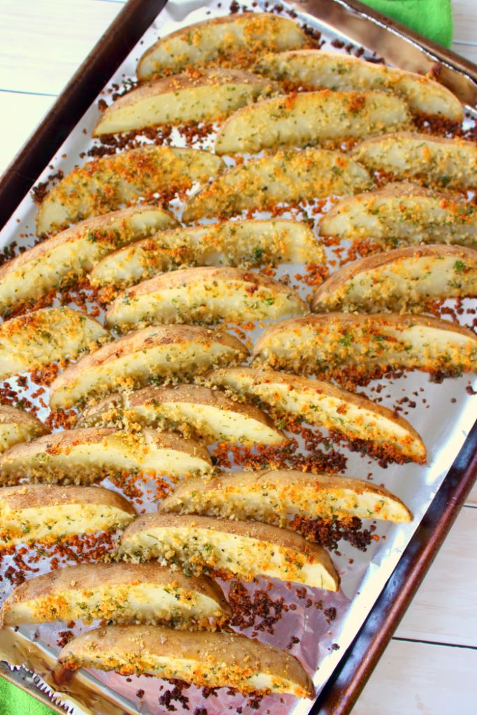 baked potato wedges on a baking sheet with seasoning sprinkled over them