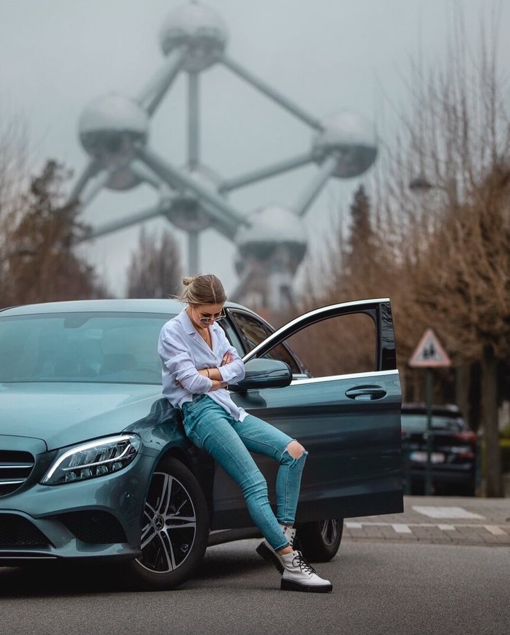 a woman sitting on the hood of a blue car