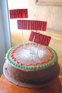 a chocolate cake with candles on top and happy birthday jesus stick in the middle, sitting on a wooden table