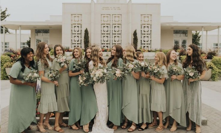 a group of women standing next to each other in front of a building with flowers