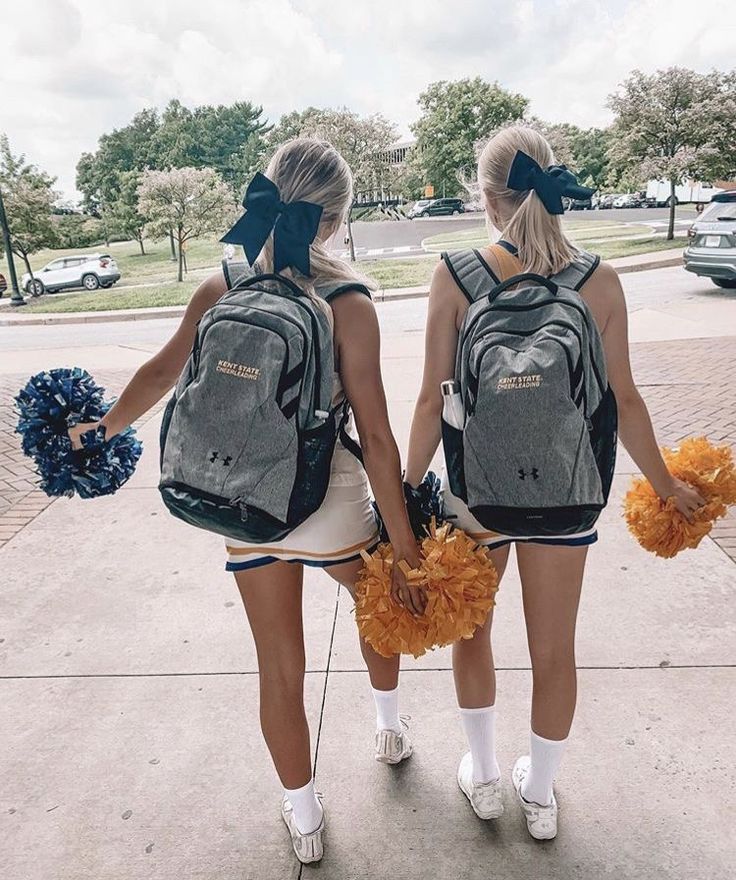 two girls with backpacks and cheerleader pom poms