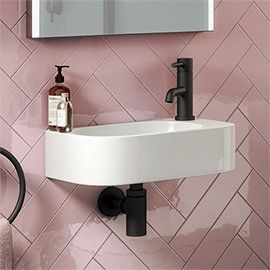 a bathroom sink and mirror with pink tiles on the wall behind it, along with toiletries