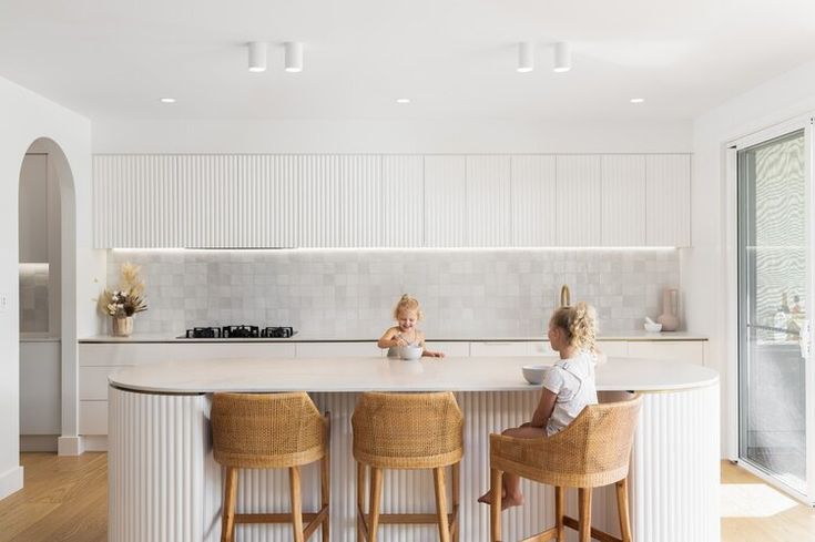 two young children sitting at a kitchen island with stools in front of the counter