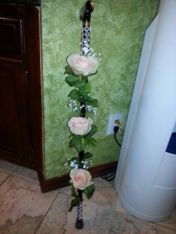 a tall vase with roses and greenery on the floor in front of a green wall