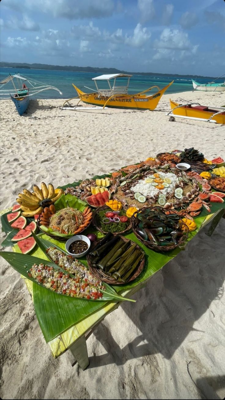 an image of food on the beach with boats in the background