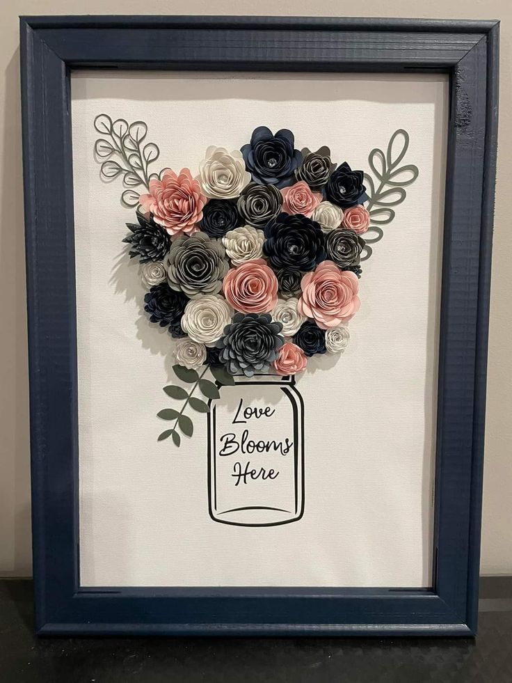 a framed paper flower arrangement with the words love blooms here