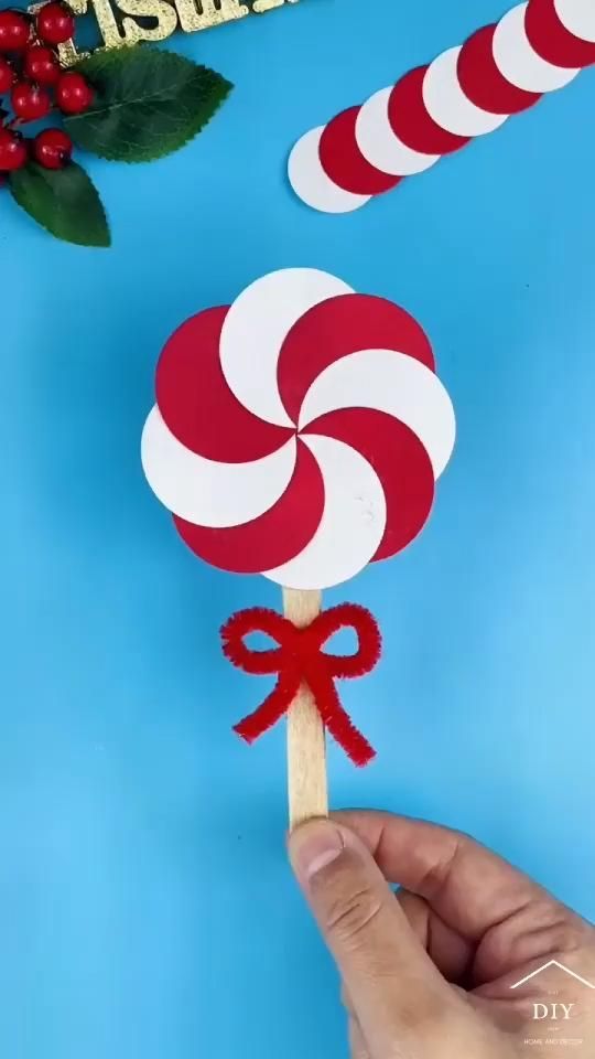 a hand holding a lollipop on top of a blue table with red and white decorations