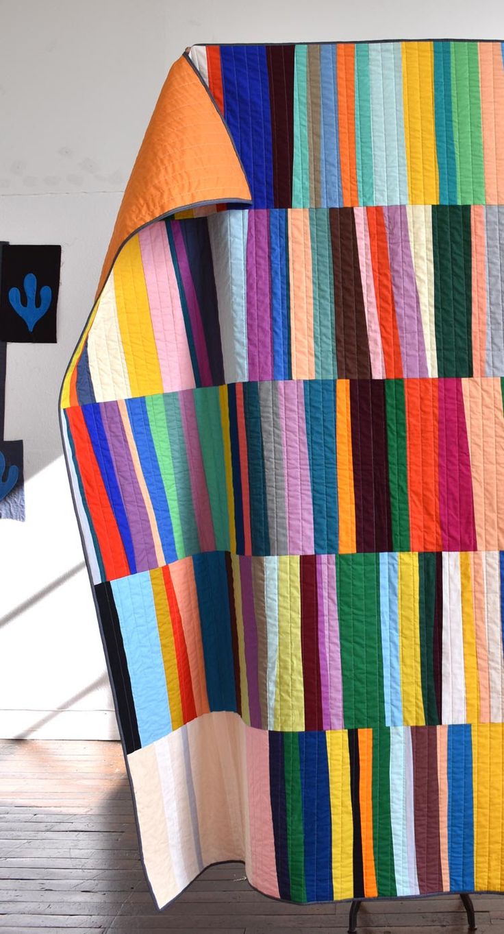 a multicolored quilt sitting on top of a wooden floor