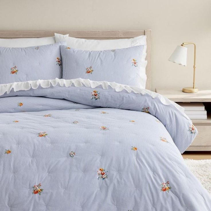 a bed with blue and white comforters in a bedroom next to a lamp on a table