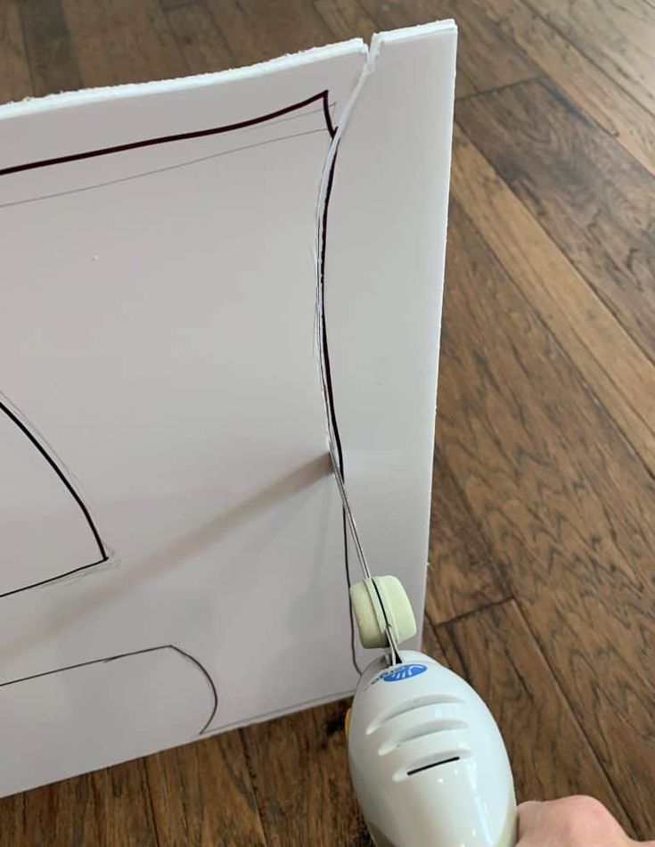 a hand holding a cord attached to a piece of paper with a drawing on it