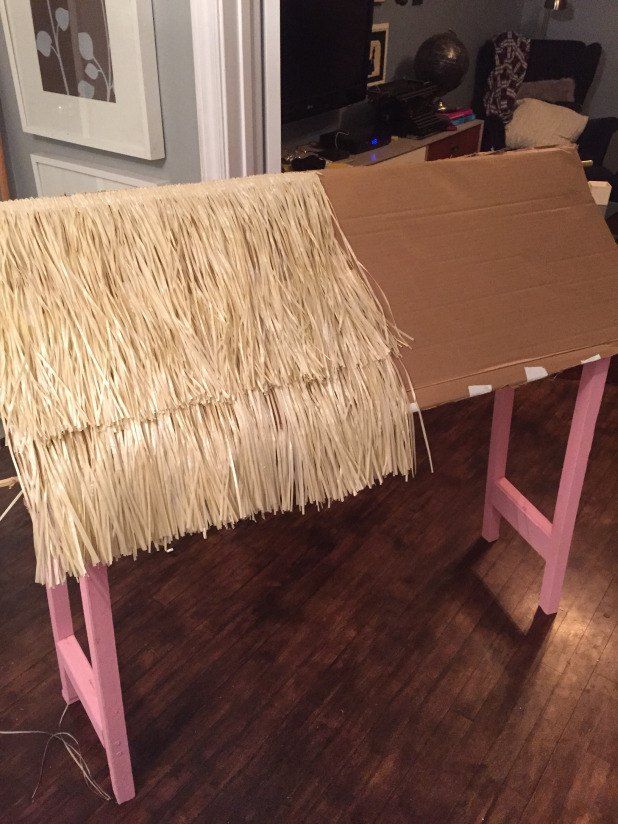 a table made out of cardboard and straw with pink legs on the floor in a living room