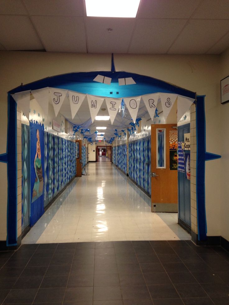 an empty hallway with blue and white decorations on the walls, along with posters hanging from the ceiling