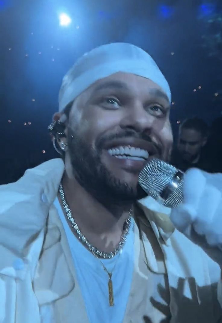 a man holding a microphone in his right hand and wearing a white hat on top of his head