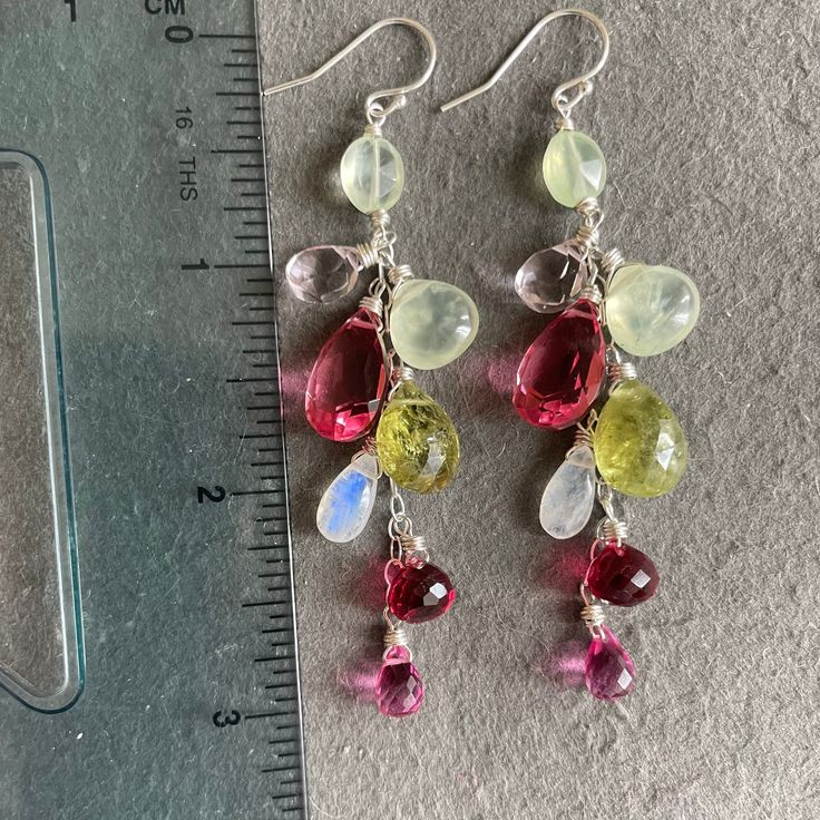 See VIDEO on instagram 2/23. From an artisan sterling silver earwires and chain I have wired in sterling silver prehnite, pink quartzes, moonstone, green garnet in a delightful dangle. There may be some variation in the green garnets from pair to pair as they are all slightly different shades. The chain, earwires and all wiring is sterling silver. The approximate length is 3”. I can also do these in other metals. The default is shown here. For any metal or earwire upgrades please shop directly from the main site, shirzay.com and select them. Fusion Wire Wrapped Dangle Jewelry, Fusion Dangle Jewelry With Natural Stones, Fusion Style Dangle Jewelry With Natural Stones, Handmade Fusion Long Drop Jewelry, Bohemian Sterling Silver Briolette Earrings, Sterling Silver Bohemian Briolette Earrings, Silver Briolette Natural Gemstones, Silver Multi-stone Dangle Gemstones, Silver Multi-stone Briolette Gemstones