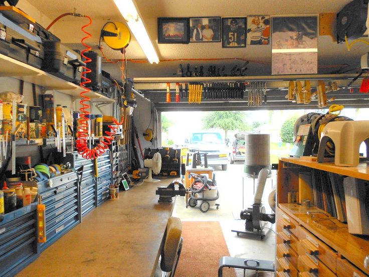 the inside of a garage with lots of tools hanging from the ceiling and shelves full of items