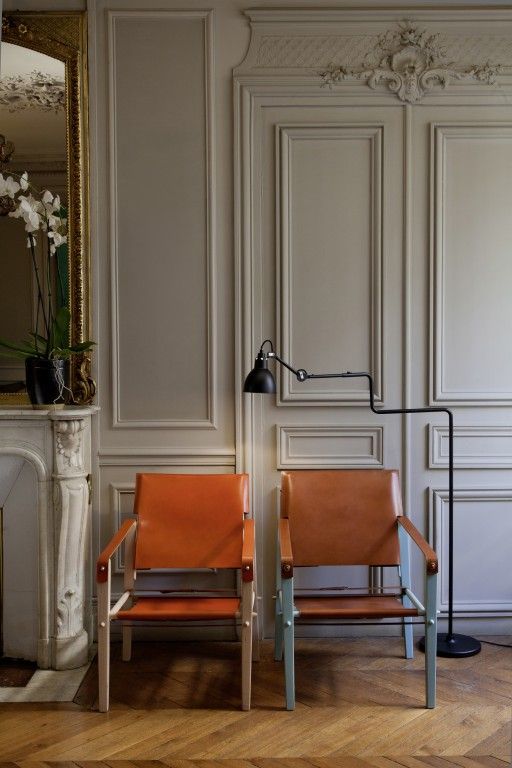 two orange chairs sitting next to each other in front of a mirror on the wall