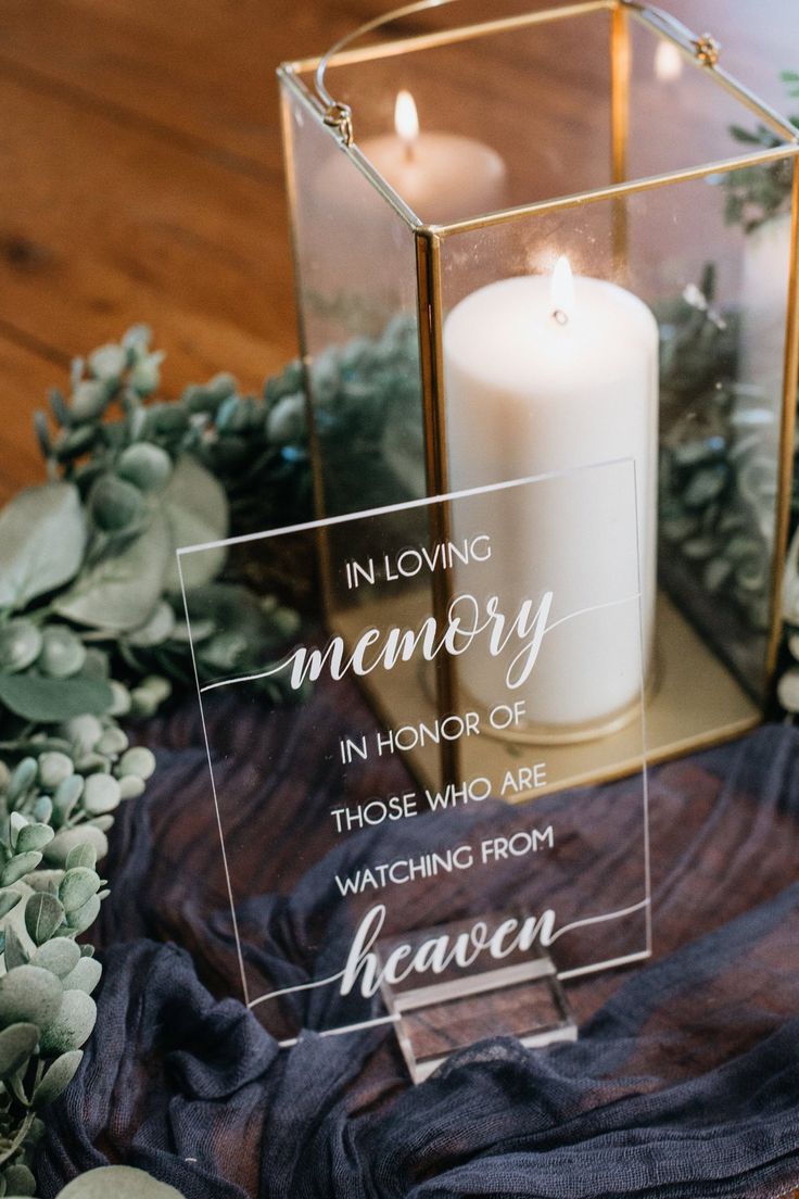 a candle is sitting on top of a table with greenery and candles in it