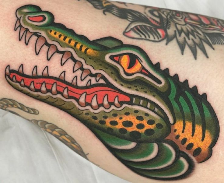 a close up of a tattoo with an alligator's head