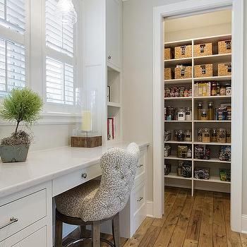 an organized pantry in the corner of a room with white cabinets and drawers, along with a bar stool