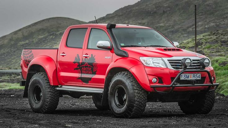 a red truck parked on top of a dirt field