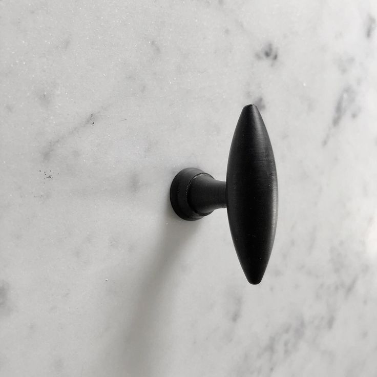 a black door handle on a white marble surface