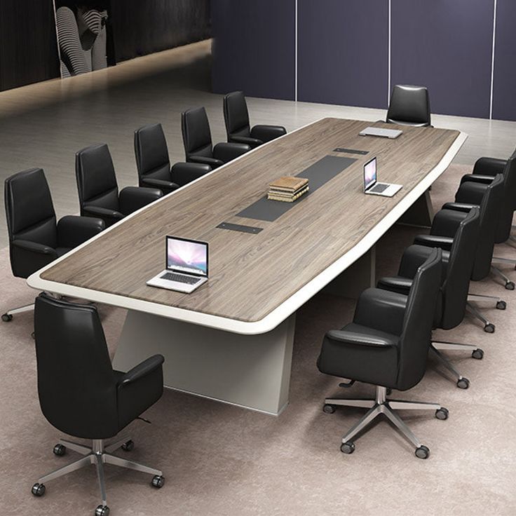 a large conference table with black chairs and a laptop computer on the desk in front of it