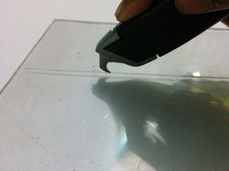 a person is using a tool to cut glass with a plastic object in the foreground